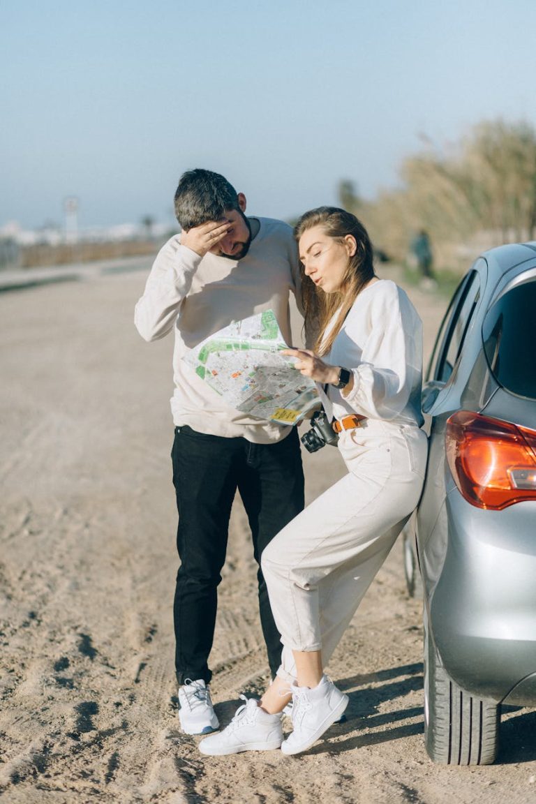 A couple stands by a car reading a map during an outdoor road trip adventure.