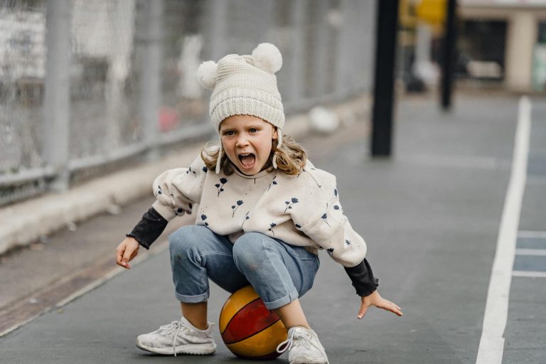 A cheerful child playing and enjoying on a sports court, full of energy and enthusiasm.