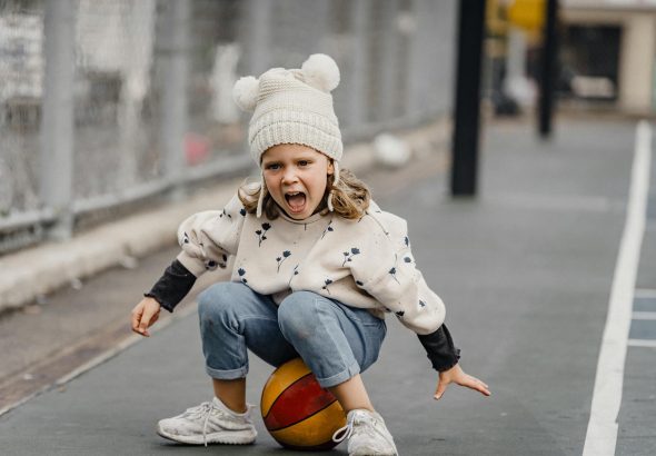 A cheerful child playing and enjoying on a sports court, full of energy and enthusiasm.