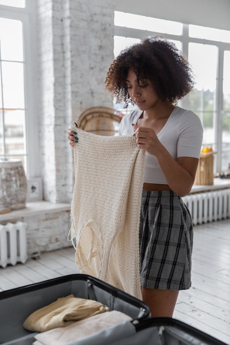 A young woman packing clothes into a suitcase for a weekend trip indoors.