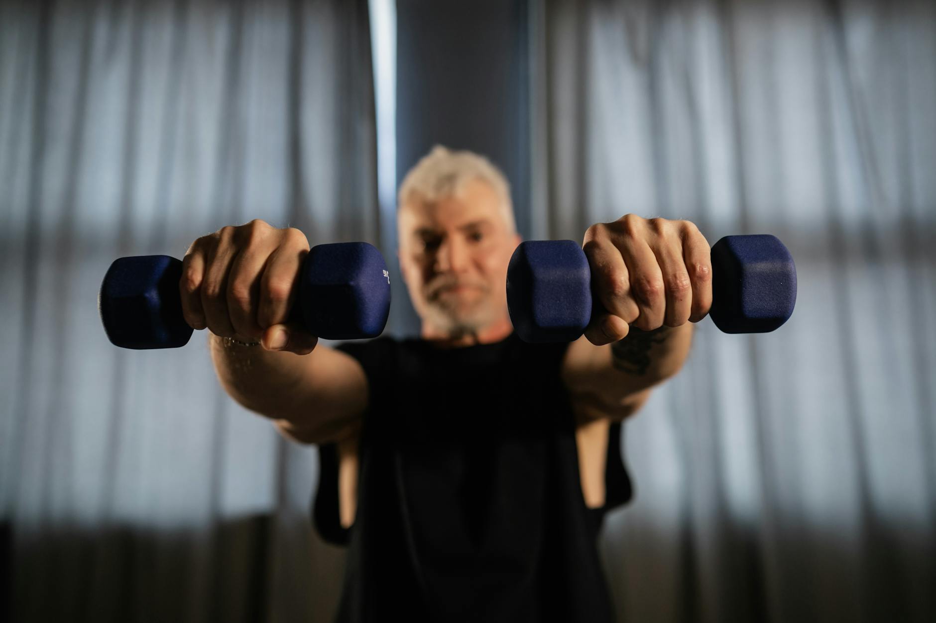 Senior man lifting dumbbells at home, embodying strength and active living.