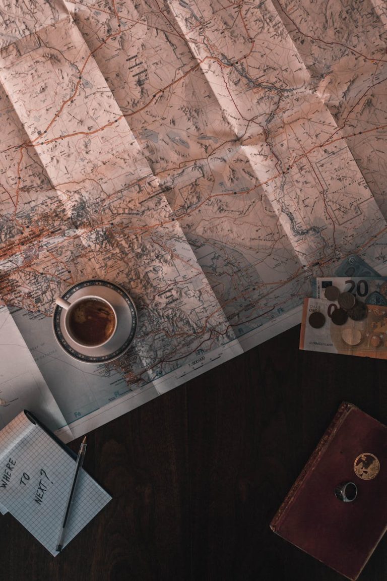 Flat lay of map, coffee, coins, and notebook for travel planning.