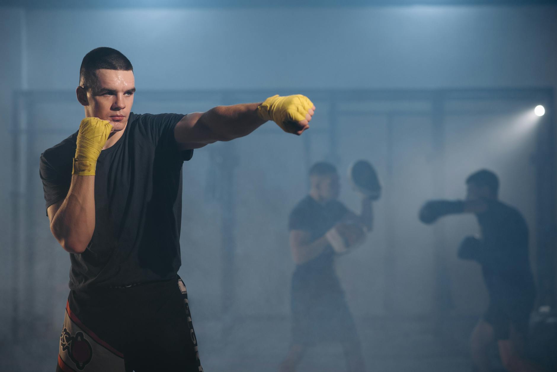 Focused fighters practicing boxing techniques with yellow gloves in a training gym.