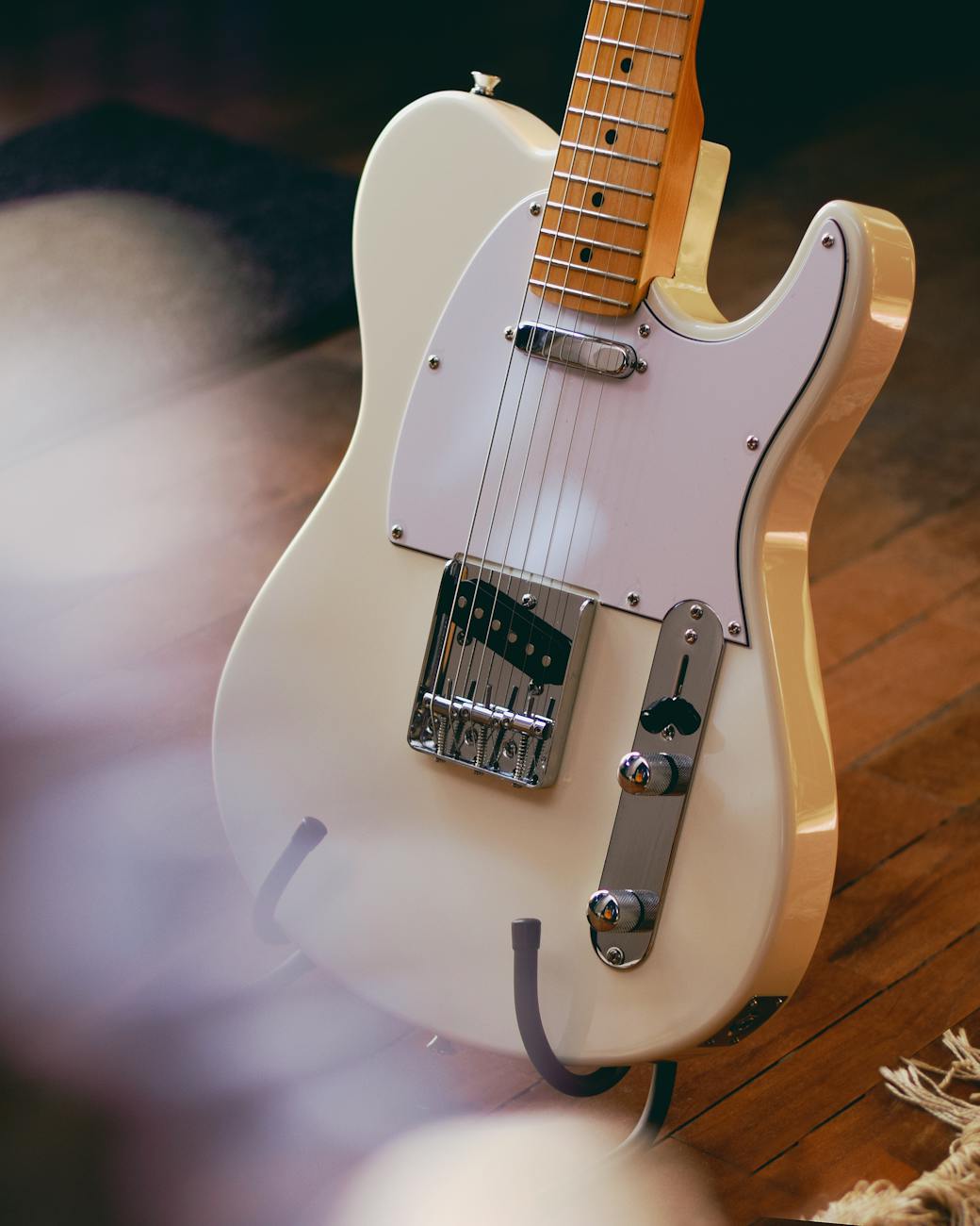 A detailed view of a vintage electric guitar resting on a wooden floor, showcasing classic design.