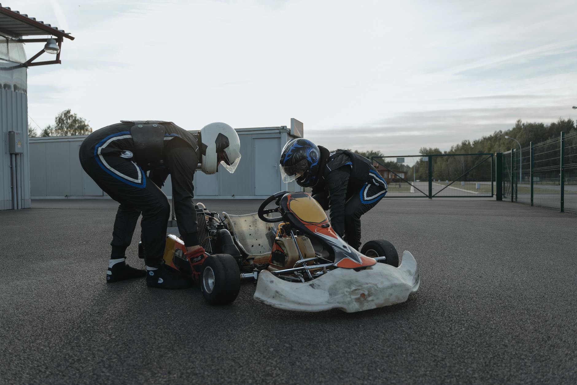 Two racers inspect their go-kart on a racetrack for an upcoming race event, enhancing sportsmanship and precision.