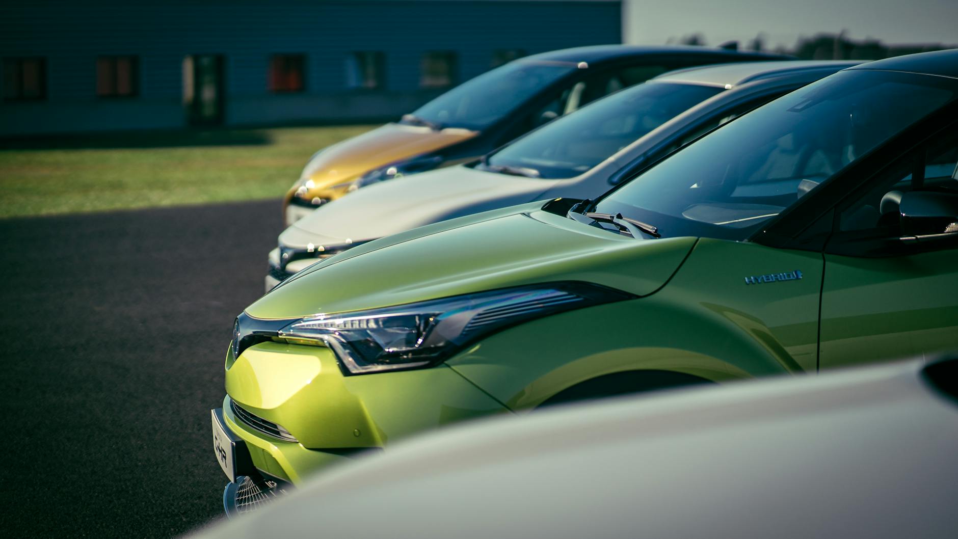 A row of brightly colored cars parked outdoors under daylight, showcasing their vibrant paint and shiny exteriors.