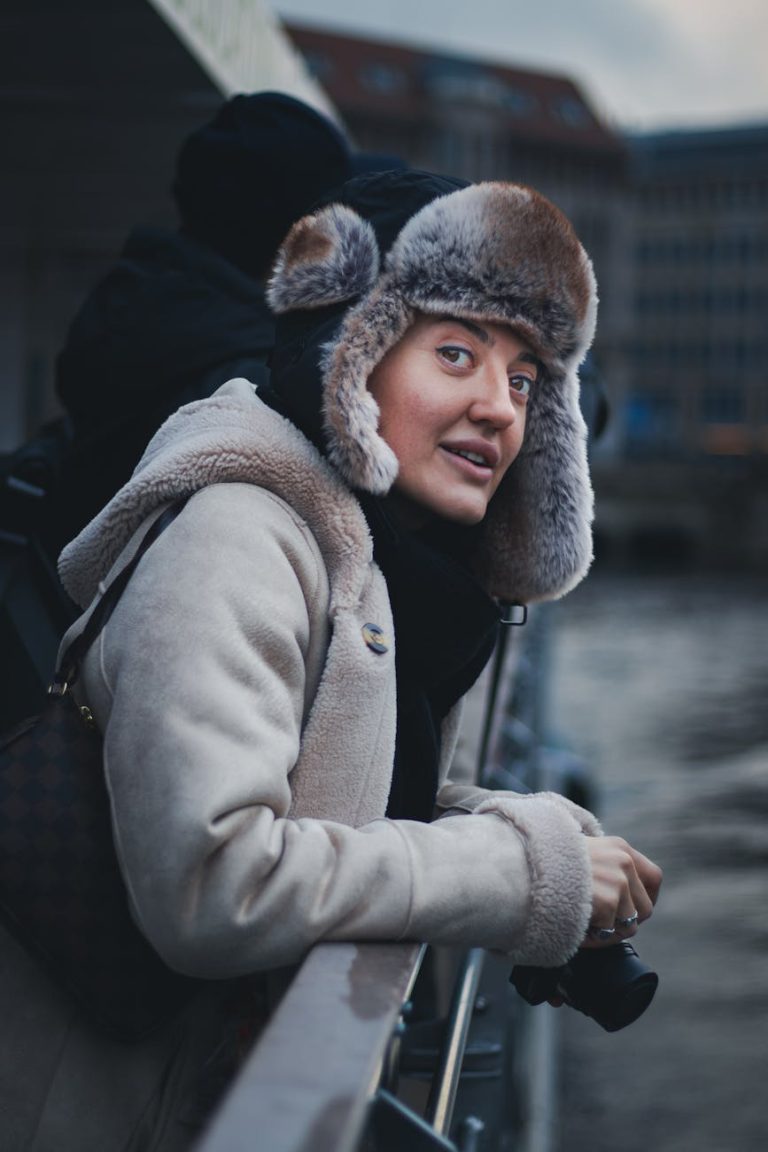 Woman wearing winter clothing on a cruise, enjoying a scenic view.