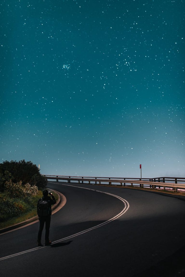 A lone traveler gazes at a breathtaking starry sky on a quiet road in Byron Bay.