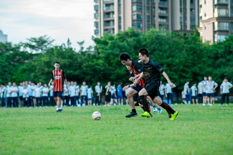 Dynamic soccer game capturing two young players in action on a grassy field surrounded by spectators.