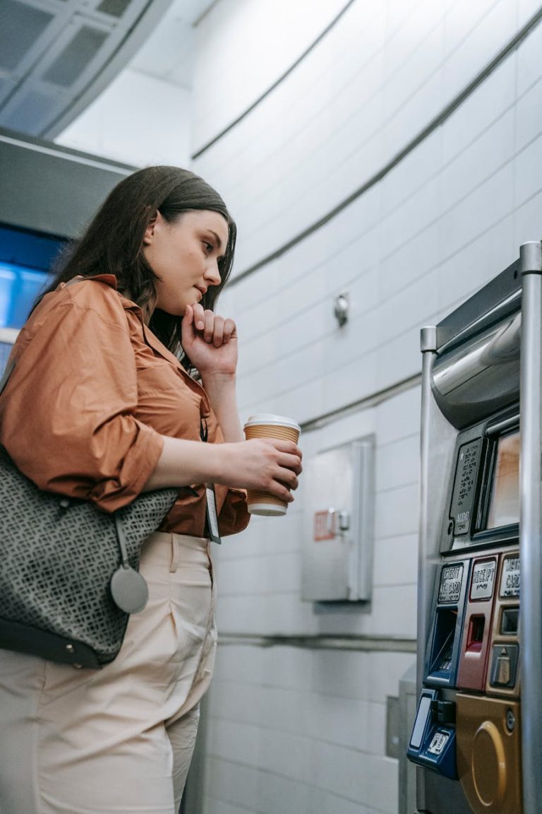 A young woman at a subway station uses a vending machine to purchase a ticket.